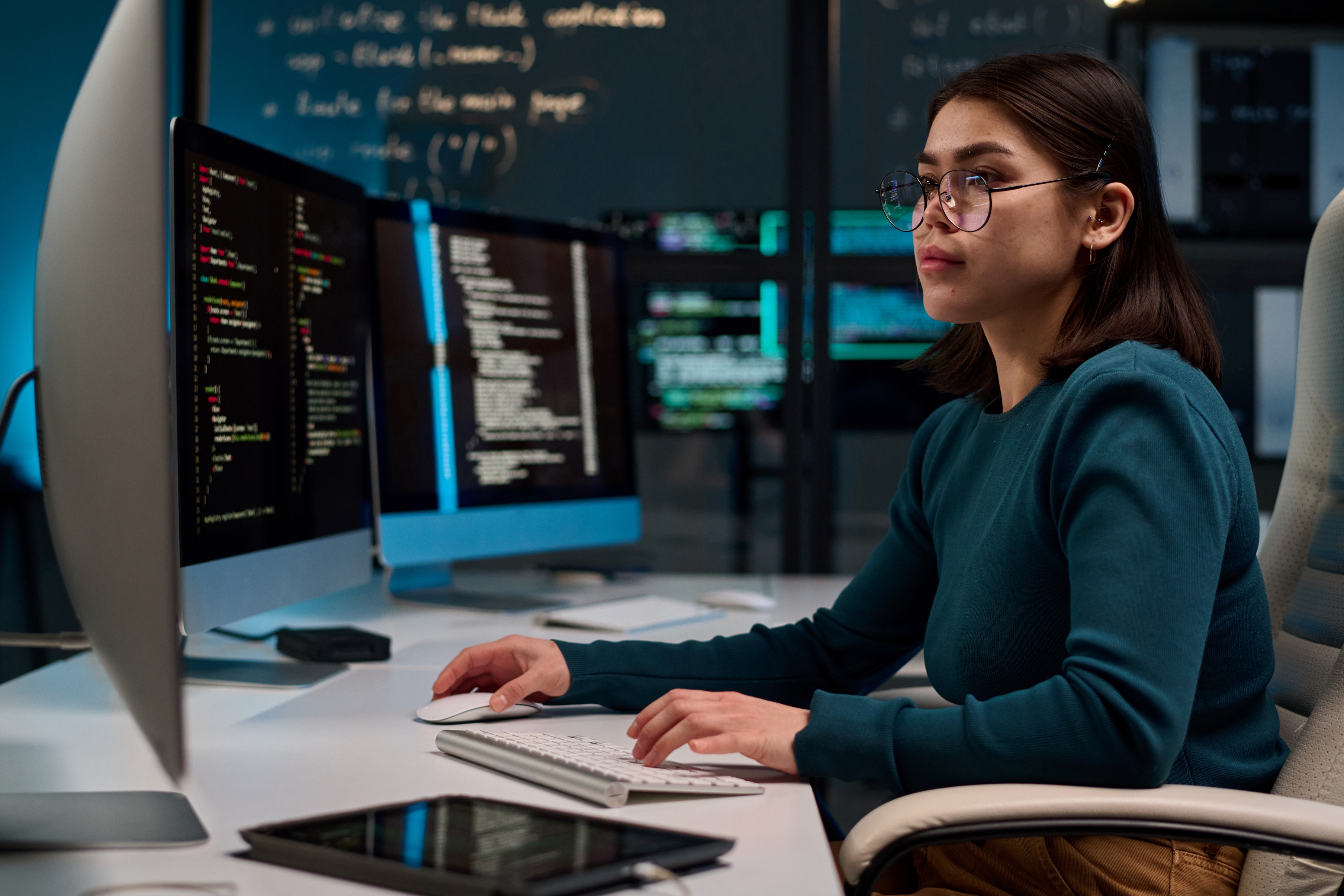 A woman in glasses is diligently working on a computer, showcasing concentration and productivity.